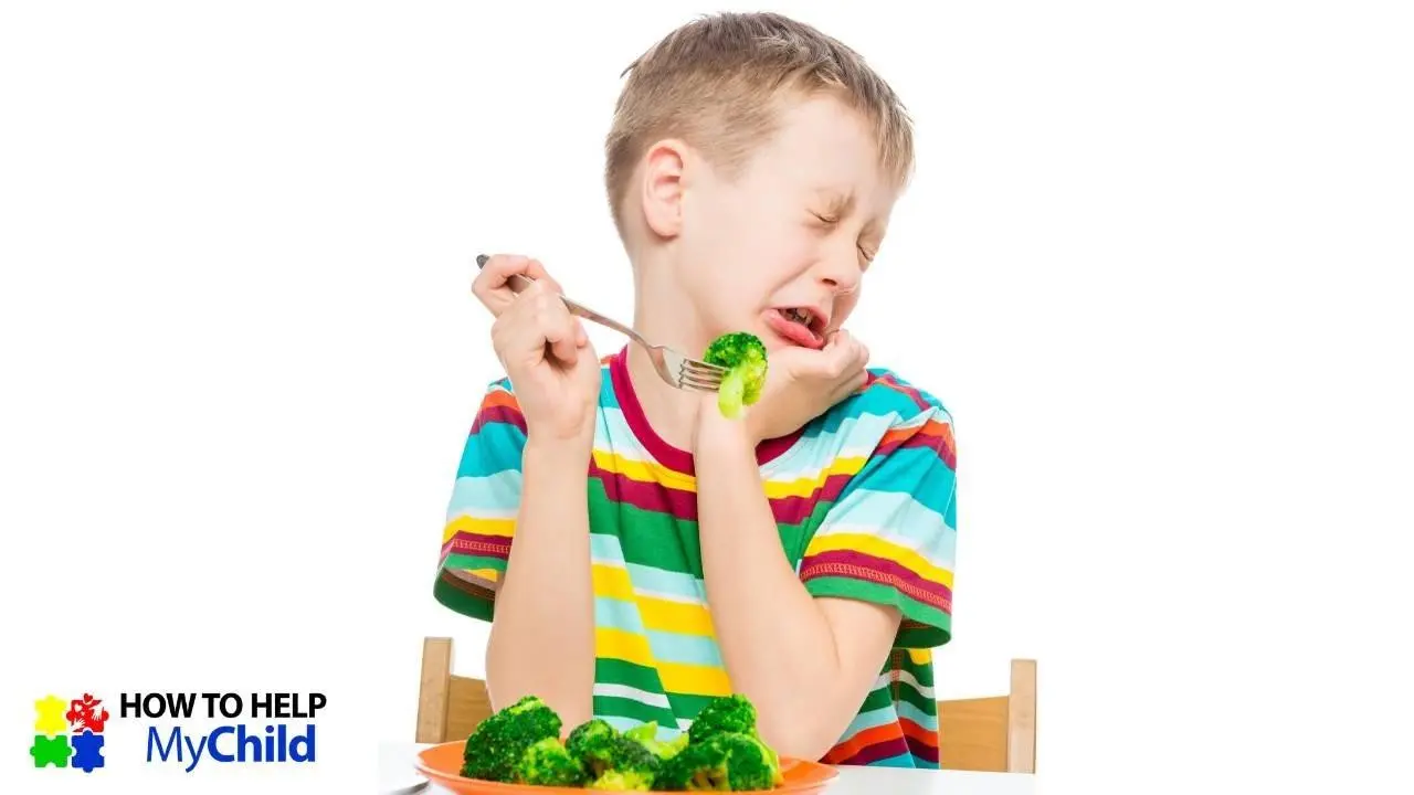 Boy in striped shirt turning his head so he doesn't eat the brocolli