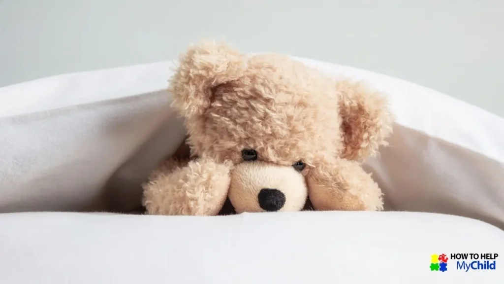 A soft, plush teddy bear peeks out from under a cozy white blanket, creating a warm and comforting bedtime scene. The bear's gentle expression conveys a sense of calm and security. In the bottom right corner, the "How to Help My Child" logo is displayed, reinforcing the theme of creating peaceful bedtime routines for children.